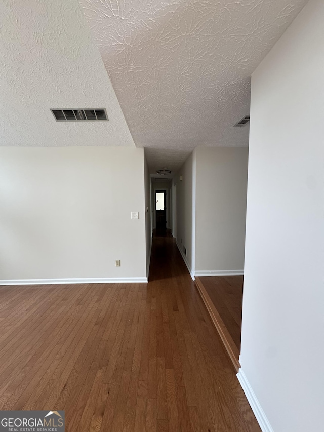 hall with wood-type flooring and a textured ceiling