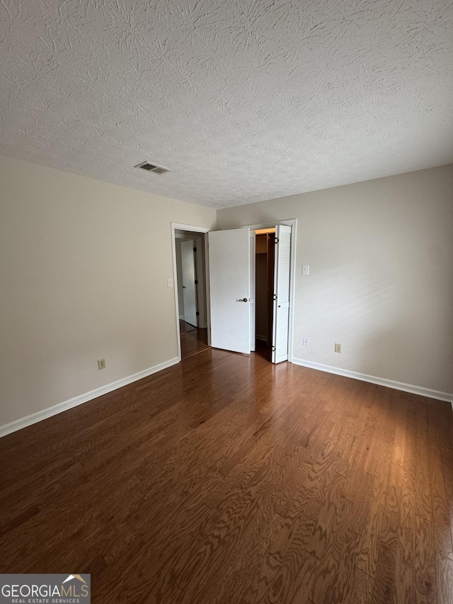 spare room with dark hardwood / wood-style flooring and a textured ceiling