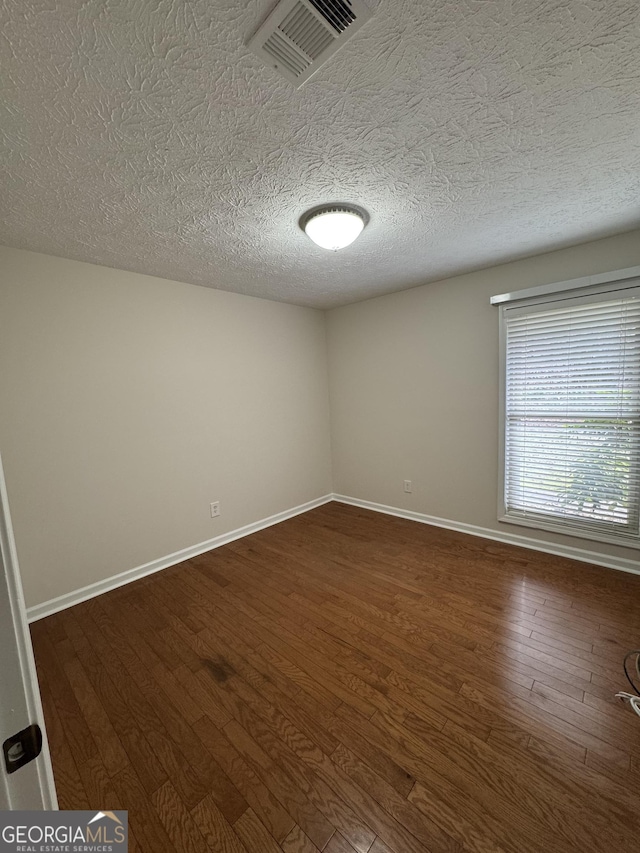 unfurnished room featuring a textured ceiling and dark hardwood / wood-style flooring