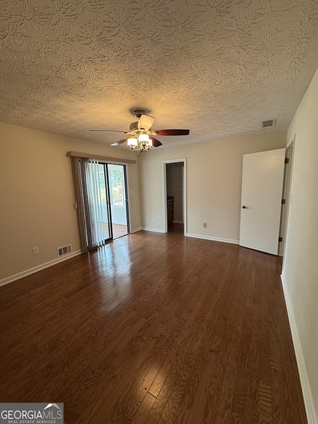 spare room featuring dark wood-type flooring, ceiling fan, and a textured ceiling