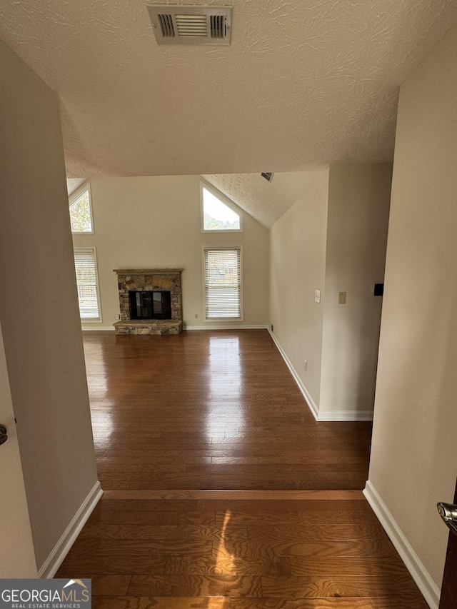 unfurnished living room with a fireplace, hardwood / wood-style flooring, a wealth of natural light, and vaulted ceiling