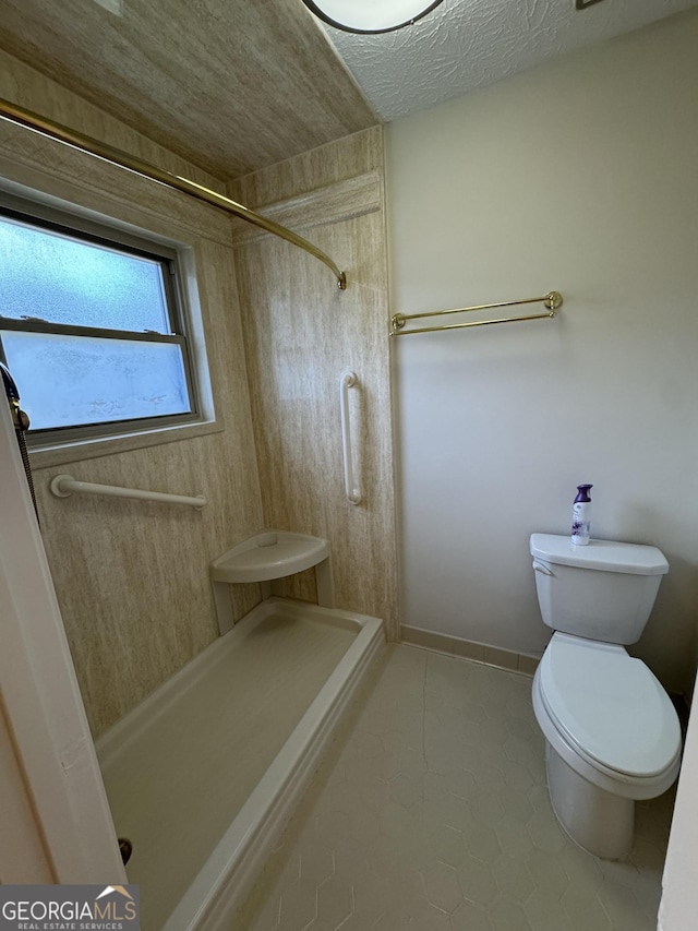 bathroom featuring walk in shower, toilet, and a textured ceiling