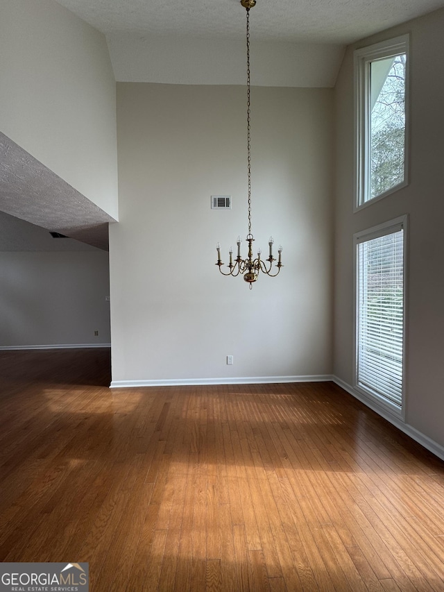 unfurnished dining area with hardwood / wood-style flooring, plenty of natural light, and a high ceiling