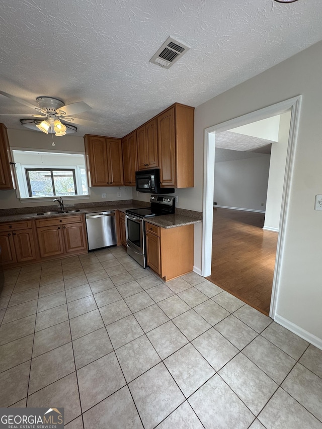 kitchen featuring sink, light tile patterned floors, stainless steel appliances, and a textured ceiling