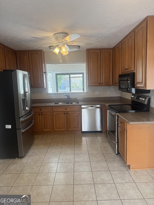 kitchen with sink, ceiling fan, appliances with stainless steel finishes, a textured ceiling, and light tile patterned flooring