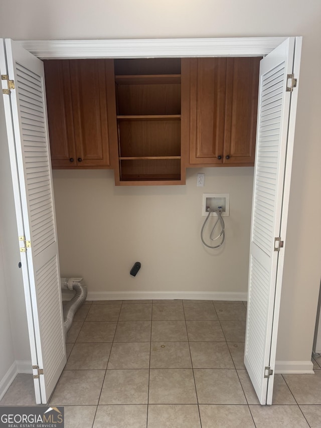 laundry room with washer hookup, cabinets, and light tile patterned flooring