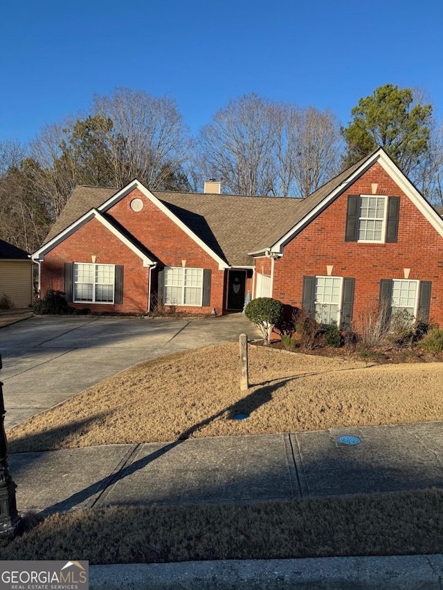 view of front of house with driveway, a shingled roof, a chimney, and brick siding