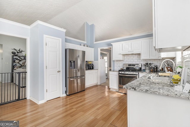 kitchen with stainless steel appliances, a sink, white cabinetry, decorative backsplash, and light wood finished floors