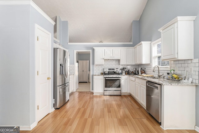 kitchen featuring under cabinet range hood, a sink, white cabinetry, appliances with stainless steel finishes, and light wood-type flooring