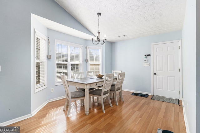 dining room featuring lofted ceiling, baseboards, wood finished floors, and a notable chandelier