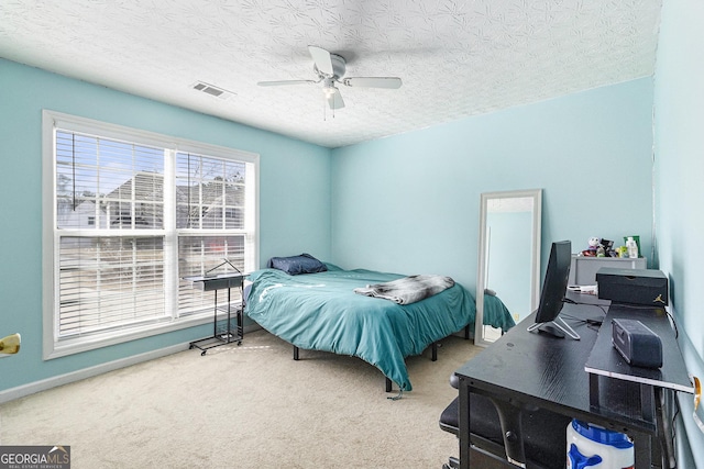 carpeted bedroom featuring a textured ceiling, visible vents, and a ceiling fan