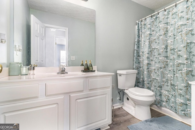 bathroom with a textured ceiling, toilet, wood finished floors, and vanity