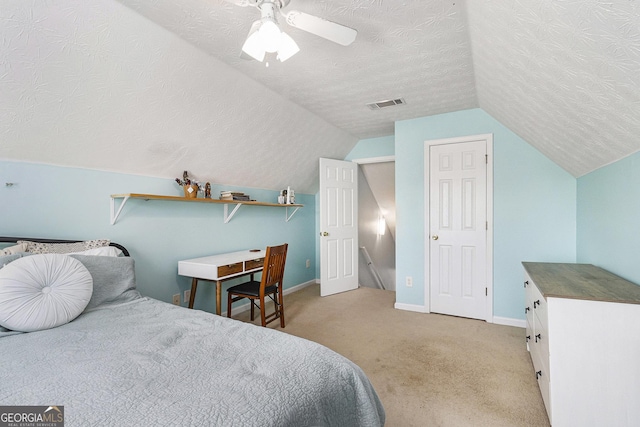 bedroom with a textured ceiling, light colored carpet, visible vents, baseboards, and vaulted ceiling