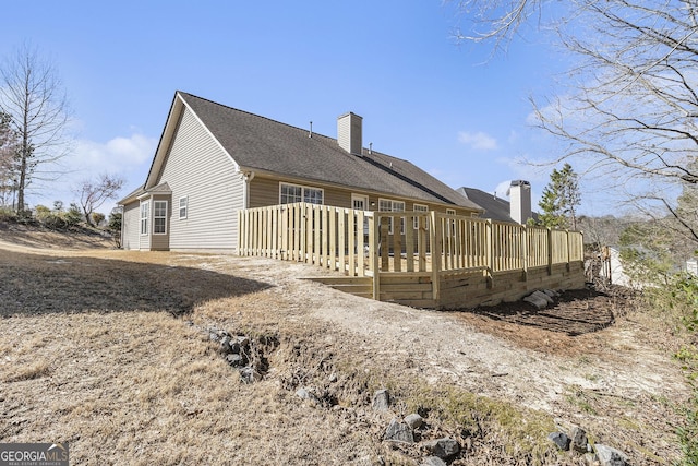 back of property featuring roof with shingles, a chimney, and a wooden deck