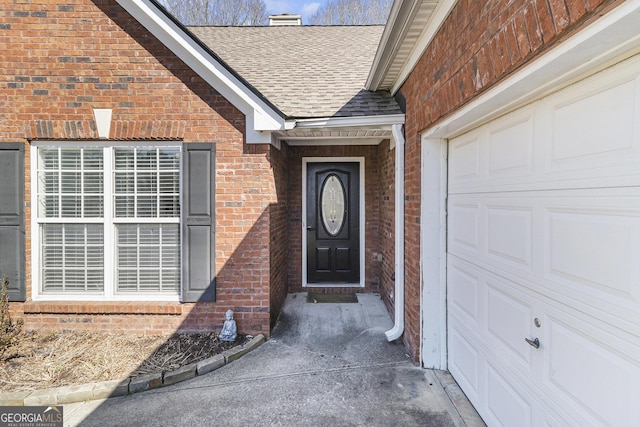 property entrance with a garage, brick siding, and roof with shingles