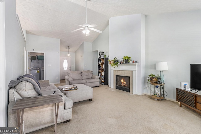 carpeted living room with a textured ceiling, high vaulted ceiling, a ceiling fan, baseboards, and a tiled fireplace