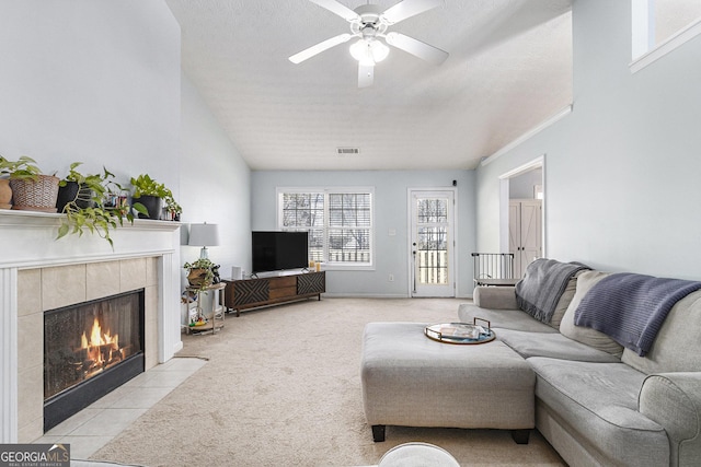 living area with a fireplace, visible vents, a ceiling fan, light carpet, and a textured ceiling