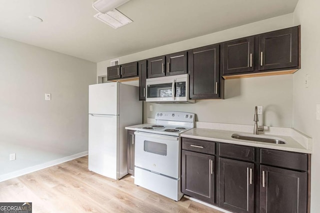 kitchen with white appliances, dark brown cabinets, sink, and light hardwood / wood-style flooring