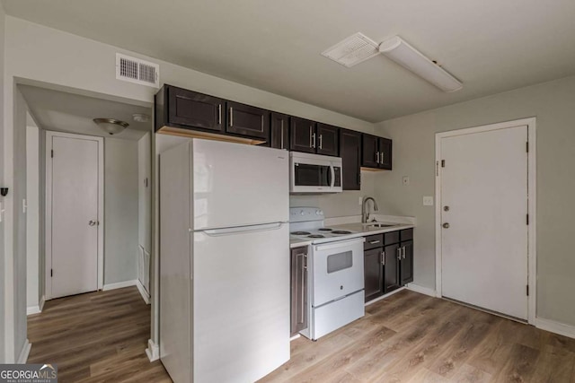 kitchen featuring sink, white appliances, dark brown cabinets, and light wood-type flooring