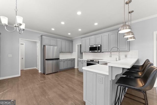 kitchen with stainless steel appliances, wood finished floors, gray cabinetry, and tasteful backsplash