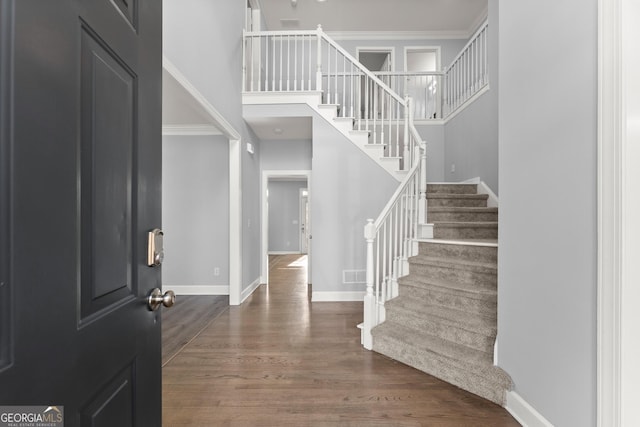 foyer entrance featuring stairs, a towering ceiling, baseboards, and wood finished floors