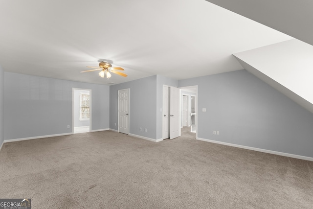 interior space with lofted ceiling, carpet flooring, a ceiling fan, and baseboards