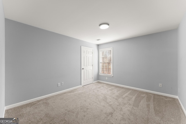 spare room with carpet, visible vents, and baseboards