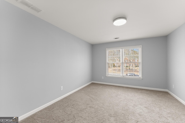 spare room with carpet floors, baseboards, and visible vents