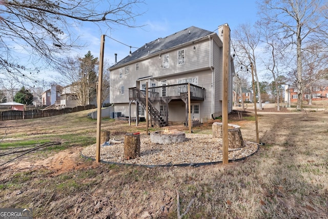 rear view of house featuring an outdoor fire pit, a chimney, stairway, fence, and a wooden deck