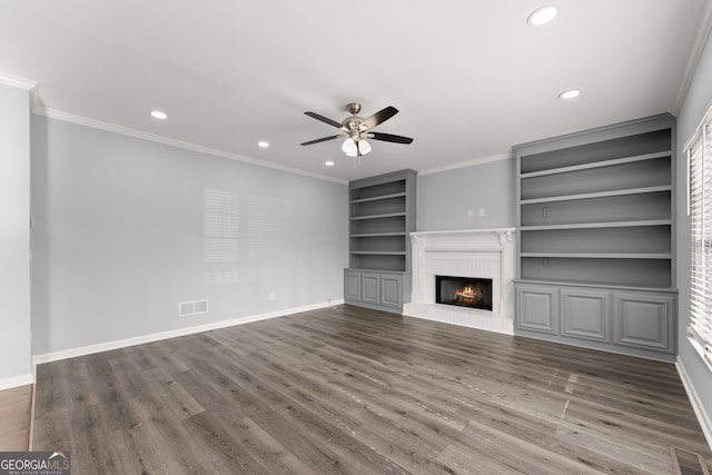 unfurnished living room featuring ornamental molding, wood finished floors, visible vents, and baseboards