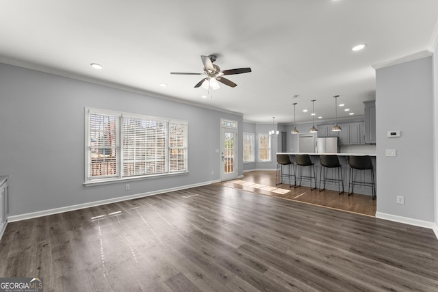 unfurnished living room featuring ornamental molding and dark wood finished floors