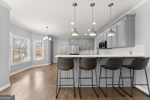 kitchen with a peninsula, tasteful backsplash, appliances with stainless steel finishes, and gray cabinetry