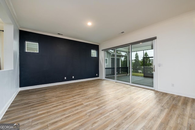 spare room featuring ornamental molding and light hardwood / wood-style floors