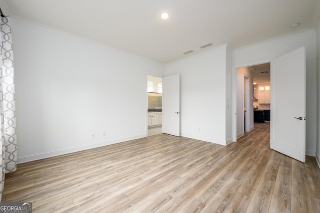 unfurnished bedroom featuring crown molding, ensuite bathroom, and light wood-type flooring