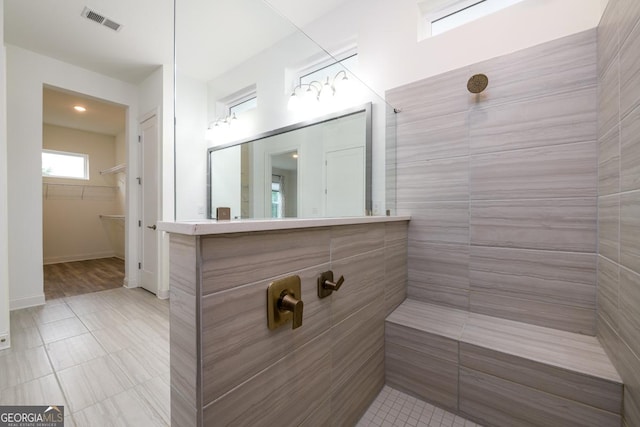 bathroom with a tile shower and vanity