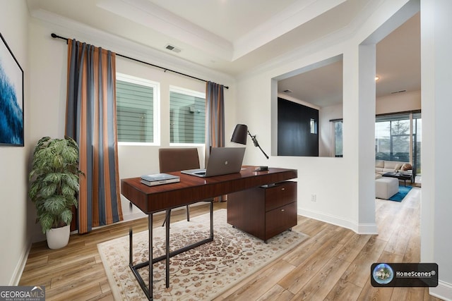 office space featuring a tray ceiling, ornamental molding, and light wood-type flooring