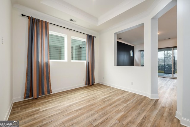 unfurnished room featuring a raised ceiling and light hardwood / wood-style flooring