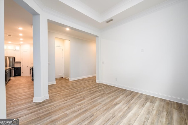 interior space featuring a tray ceiling, ornamental molding, and light hardwood / wood-style floors