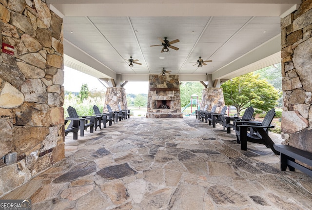 view of patio with ceiling fan and an outdoor stone fireplace