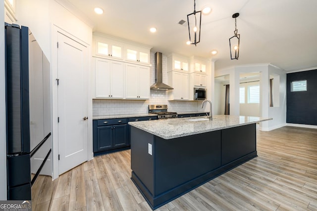 kitchen with white cabinetry, stainless steel range oven, wall chimney exhaust hood, and blue cabinets