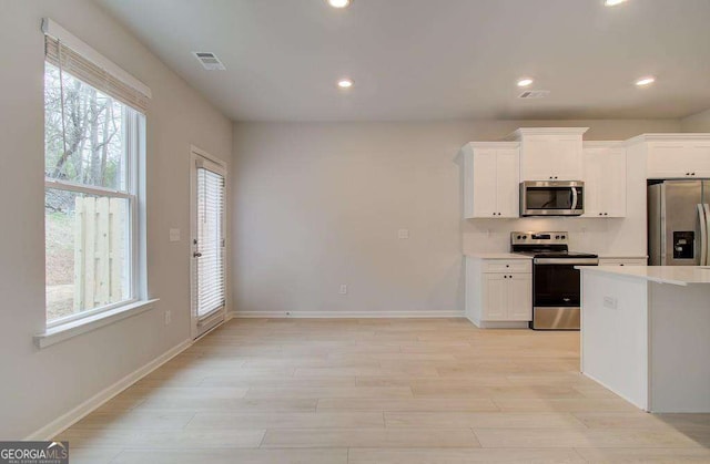 kitchen with recessed lighting, light wood-style floors, white cabinets, light countertops, and appliances with stainless steel finishes