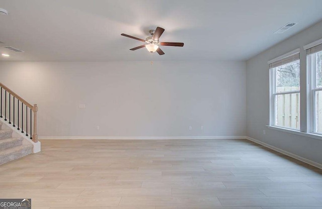 unfurnished room with stairs, light wood finished floors, visible vents, and baseboards