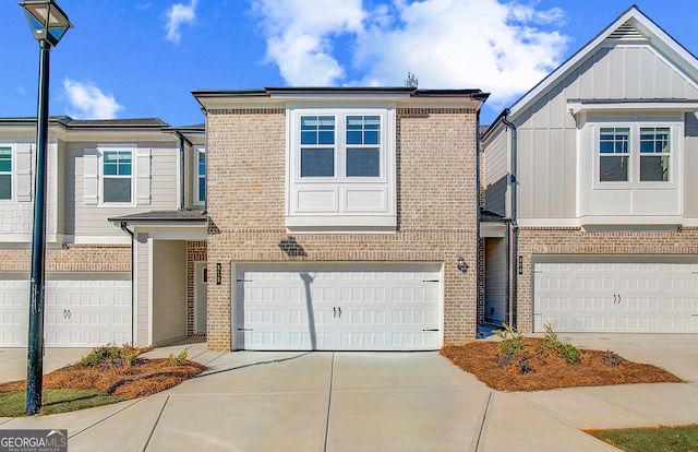 townhome / multi-family property with an attached garage, driveway, board and batten siding, and brick siding