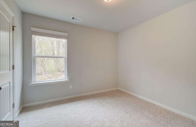 carpeted spare room featuring visible vents and baseboards