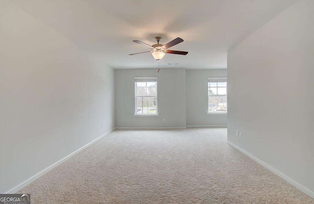 spare room with light carpet, plenty of natural light, baseboards, and ceiling fan