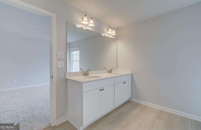 bathroom with a sink, baseboards, and double vanity