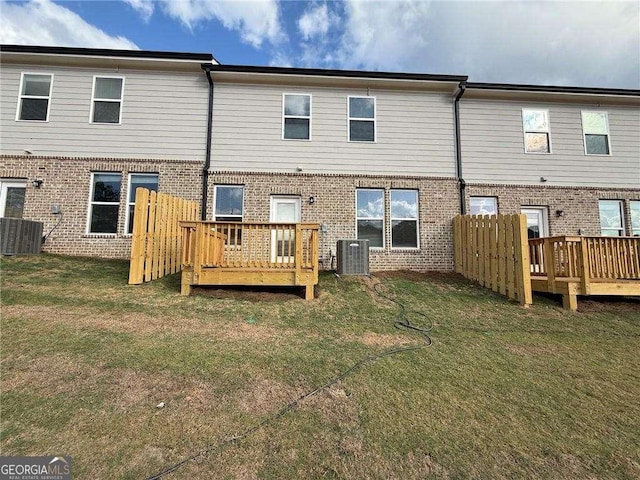 rear view of house with brick siding, a lawn, a wooden deck, and central air condition unit