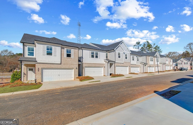 view of property featuring a residential view, concrete driveway, brick siding, and an attached garage