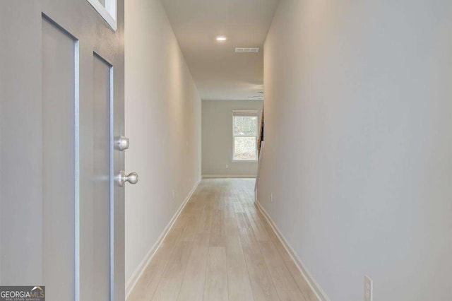 hallway featuring light wood finished floors, visible vents, and baseboards