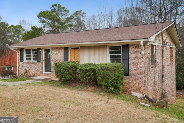 ranch-style house with brick siding, roof with shingles, and a front yard